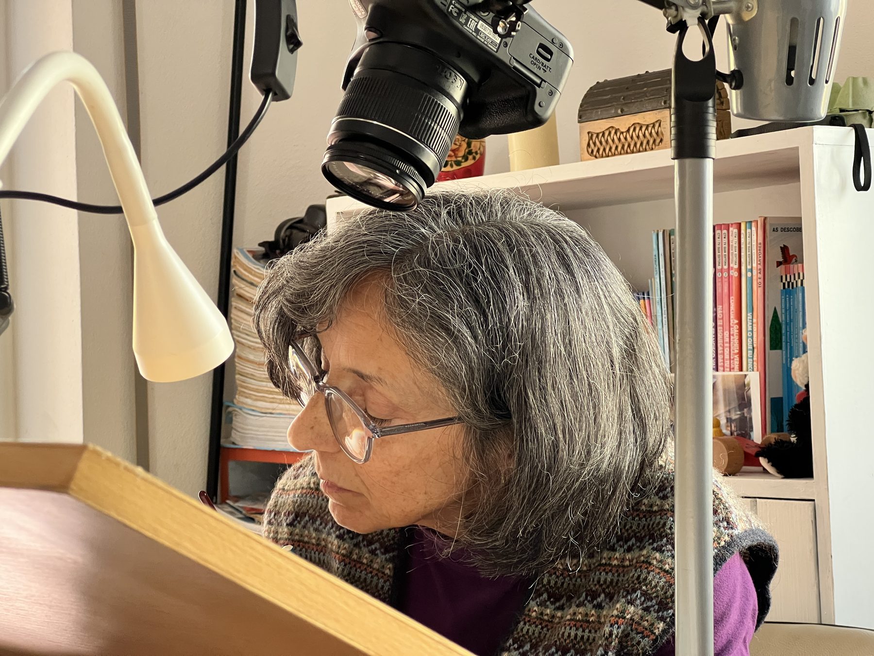 Ana Soares no atelier, concentrada, com a câmara com que fotografa as obras